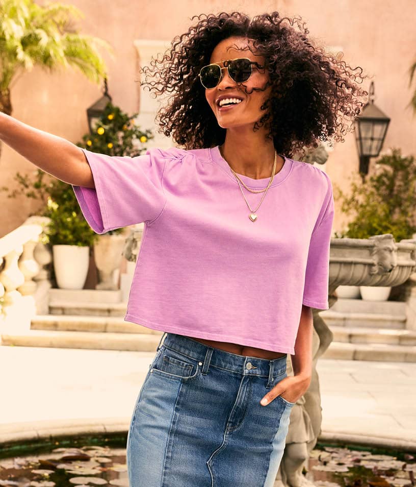 Image of woman wearing a pink tee and denim skirt