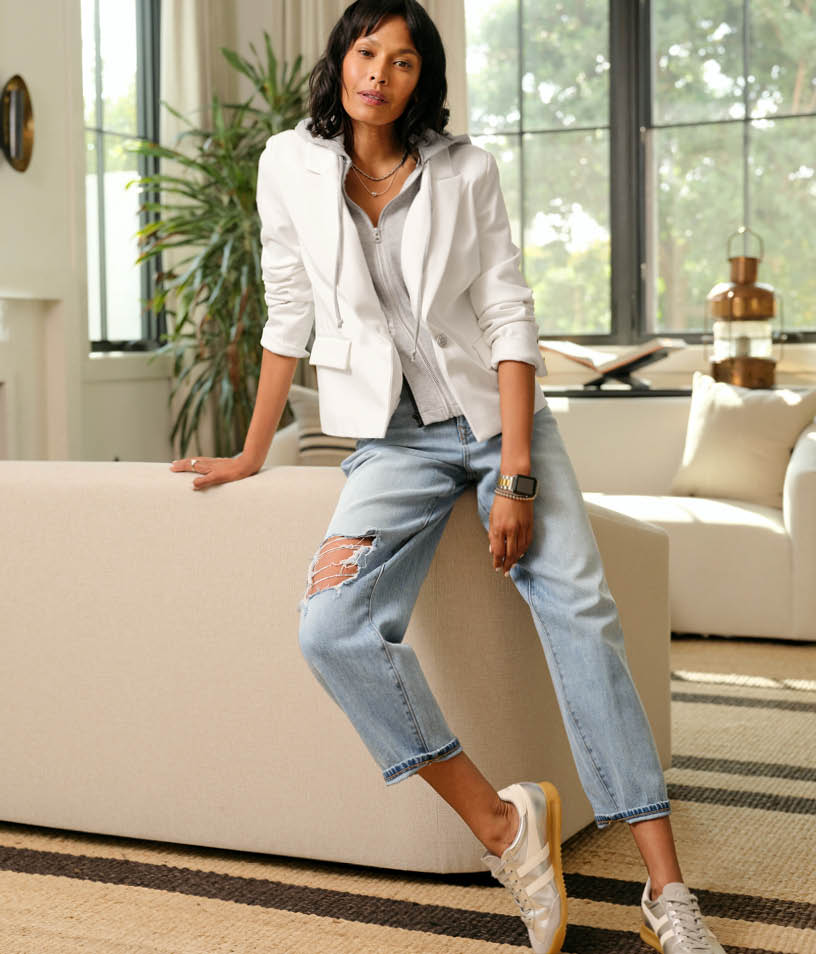 Image of woman wearing white blazer and blue jeans. 