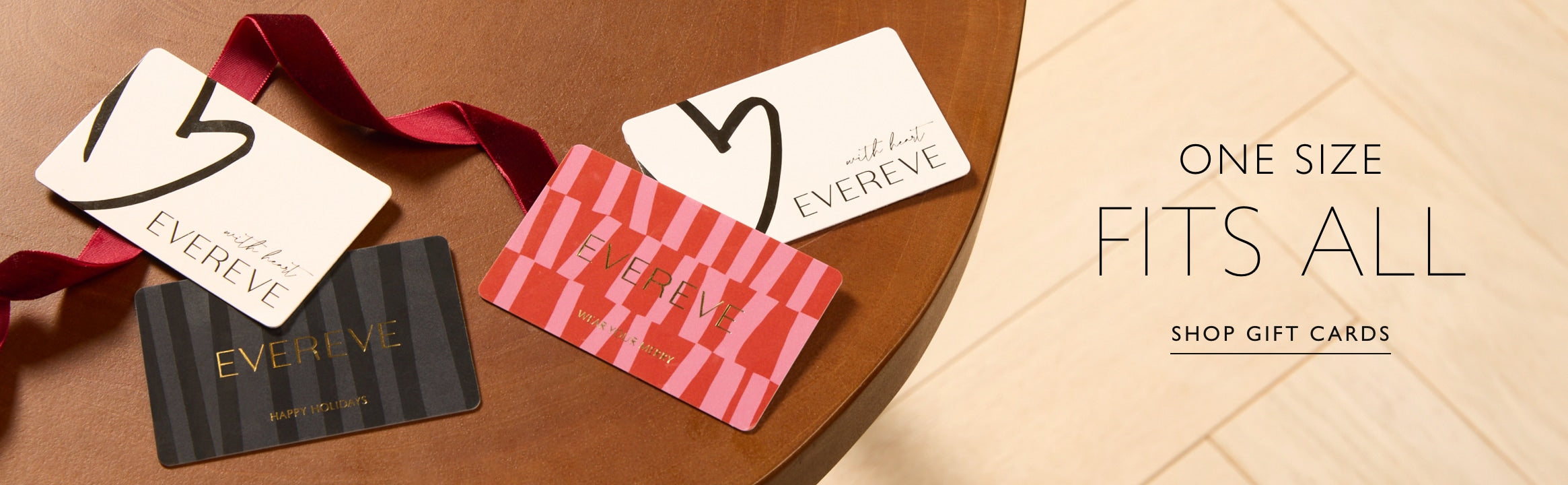 Several EVEREVE gift cards on a wooden table. Text over image reads: One size fits all, Shop gift cards.